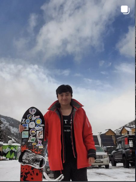 Standing with a sticker-covered snowboard